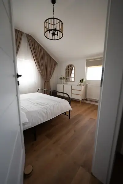 The double room from the doorway: the bed, the white dresser and the arched mirror