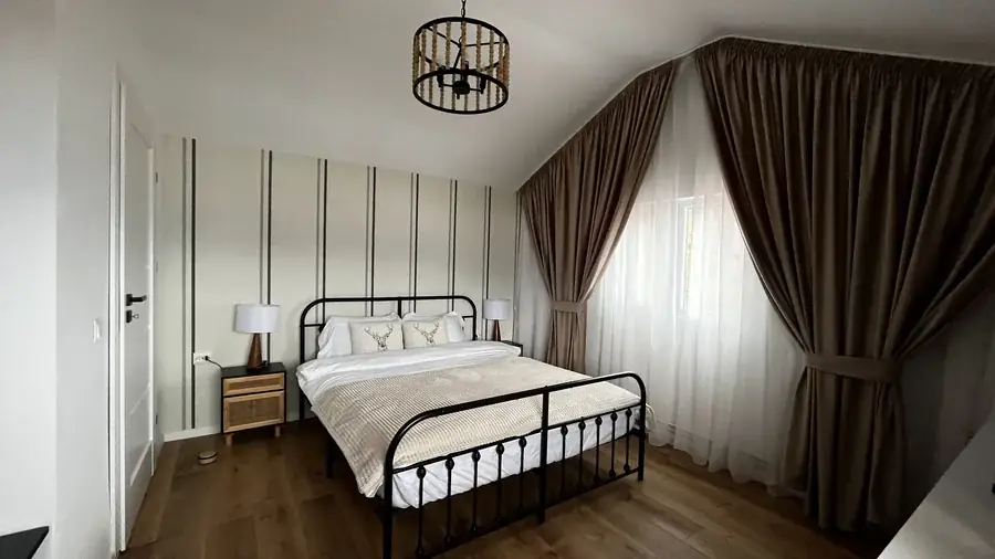 The double room, with striped wallpaper, a double bed and rattan bedside tables with lamps