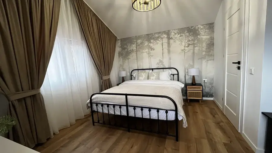 The queen bedroom, with misty-forest wallpaper, heavy curtains and wooden floors