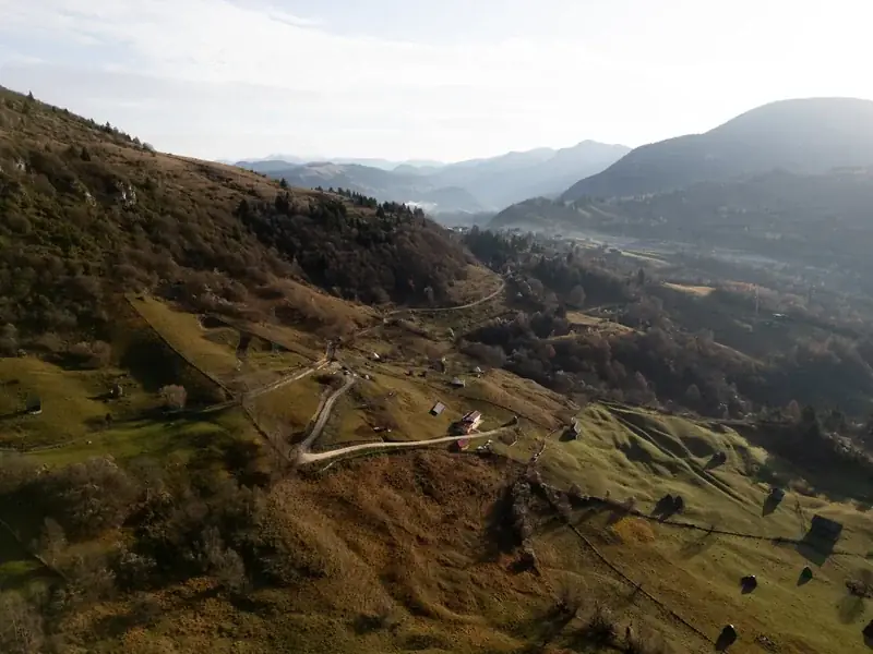 Drone view of a mountain track winding across the hills, with the mountains in haze