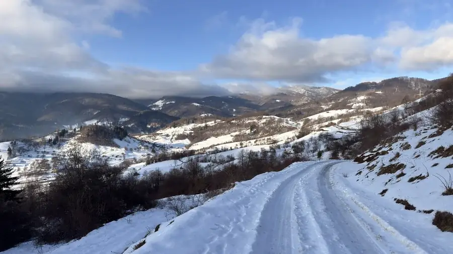 The access road to the house in winter, along the snowy hillside