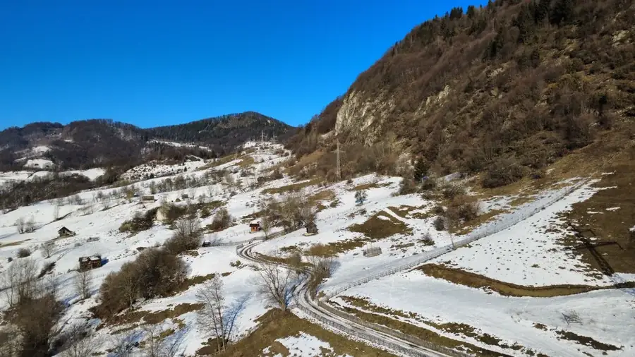A road winding through snowy hills under a clear winter sky