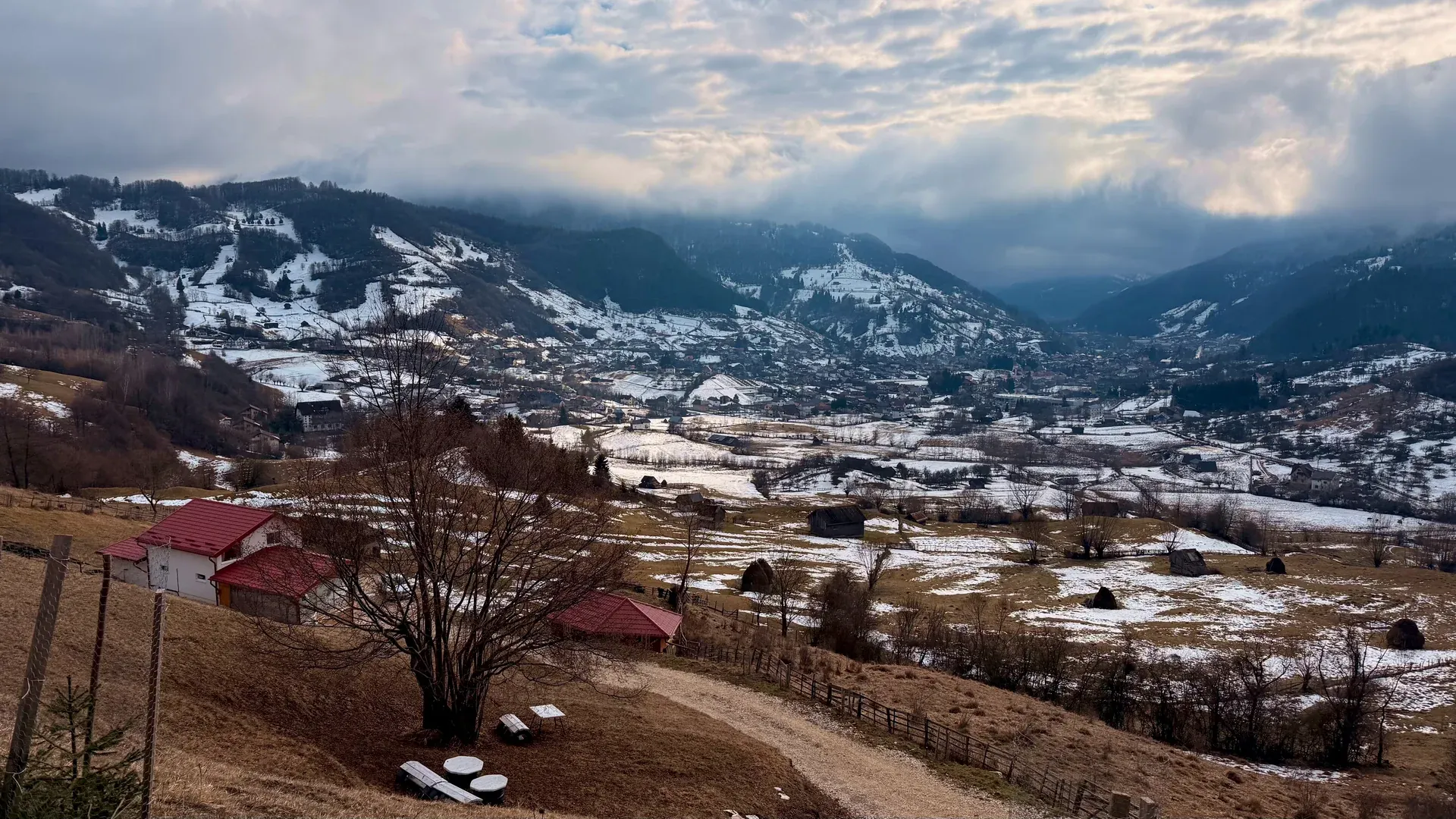 Winter from the house: red roofs in front, the village and snowy mountains beyond
